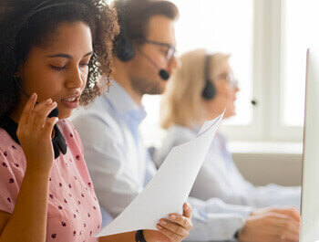 Close up view of a call center with three people on headsets